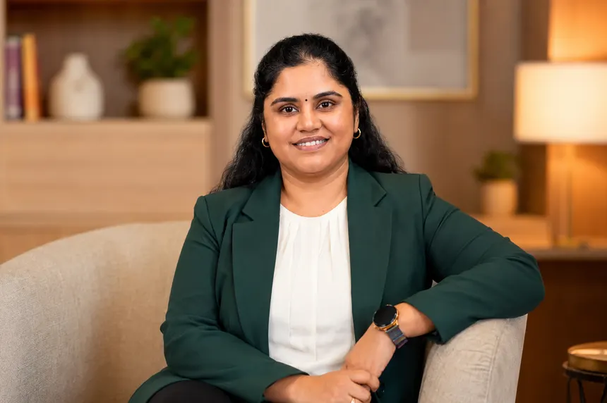 Revathi Varadarajalou in a green blazer, seated in a warmly lit room with a relaxed, welcoming expression