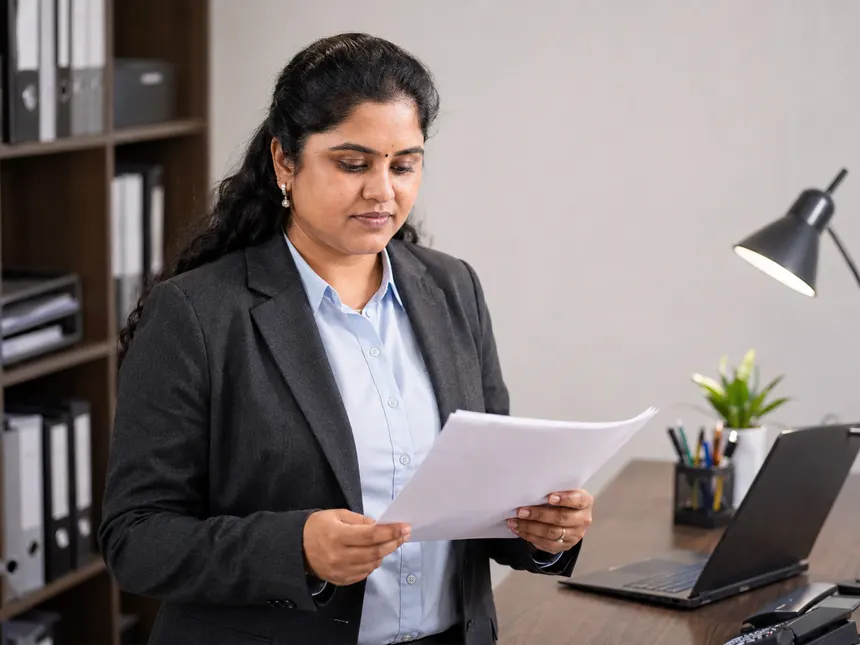 Revathi Varadarajalou reviewing a document at her desk beside shelves of case binders